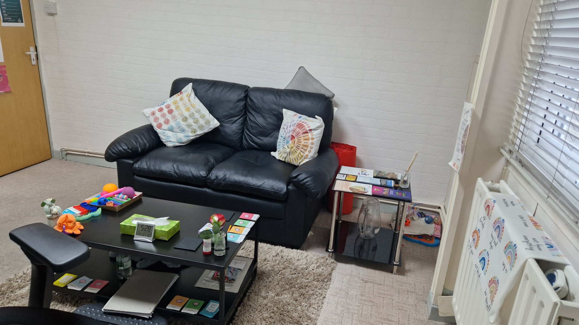Seating area in the counselling room with cushions and therapy resources